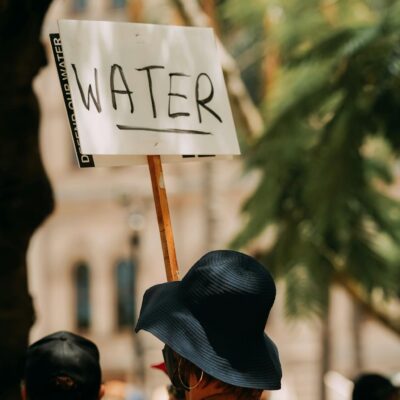 Person in Hat and with Banner with Water Text